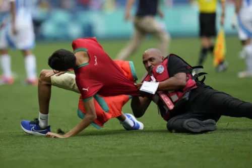 Paris 2024: A fan aggressively being prevented by a steward from getting into the pitch. 