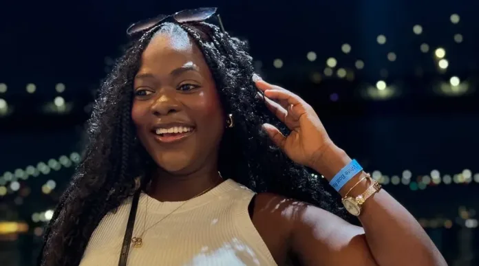 Asantewaa's posing in front of a scenic backdrop in the USA, wearing a stylish outfit and smiling confidently.