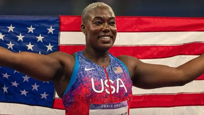 Image of Annette Echikunwoke, a the Olympics 2024 Silver Medal Winner, smiling and posing for a photo, with a USA flag