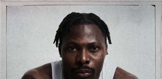 Asake Sets Record: Asake posing confidently during an album photoshoot, dressed in stylish contemporary attire, reflecting his Afrobeats influence and global music success.