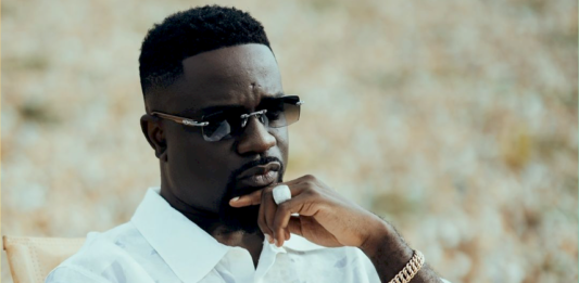 Sarkodie sitting on a chair in a video shot.