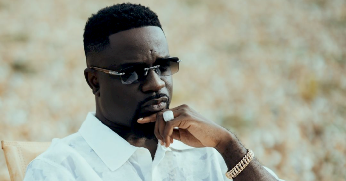 Sarkodie sitting on a chair in a video shot.