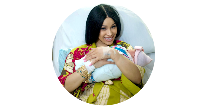 Cardi B holding her newborn daughter in her arms, smiling warmly, dressed in a casual outfit, with soft lighting creating a heartwarming moment.