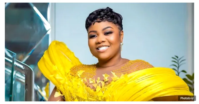 Empress Gifty poses confidently in a beautifully designed dress, showcasing her elegant style. The gospel singer stands in front of the camera with grace, smiling as she effortlessly highlights the intricate details of her glamorous outfit